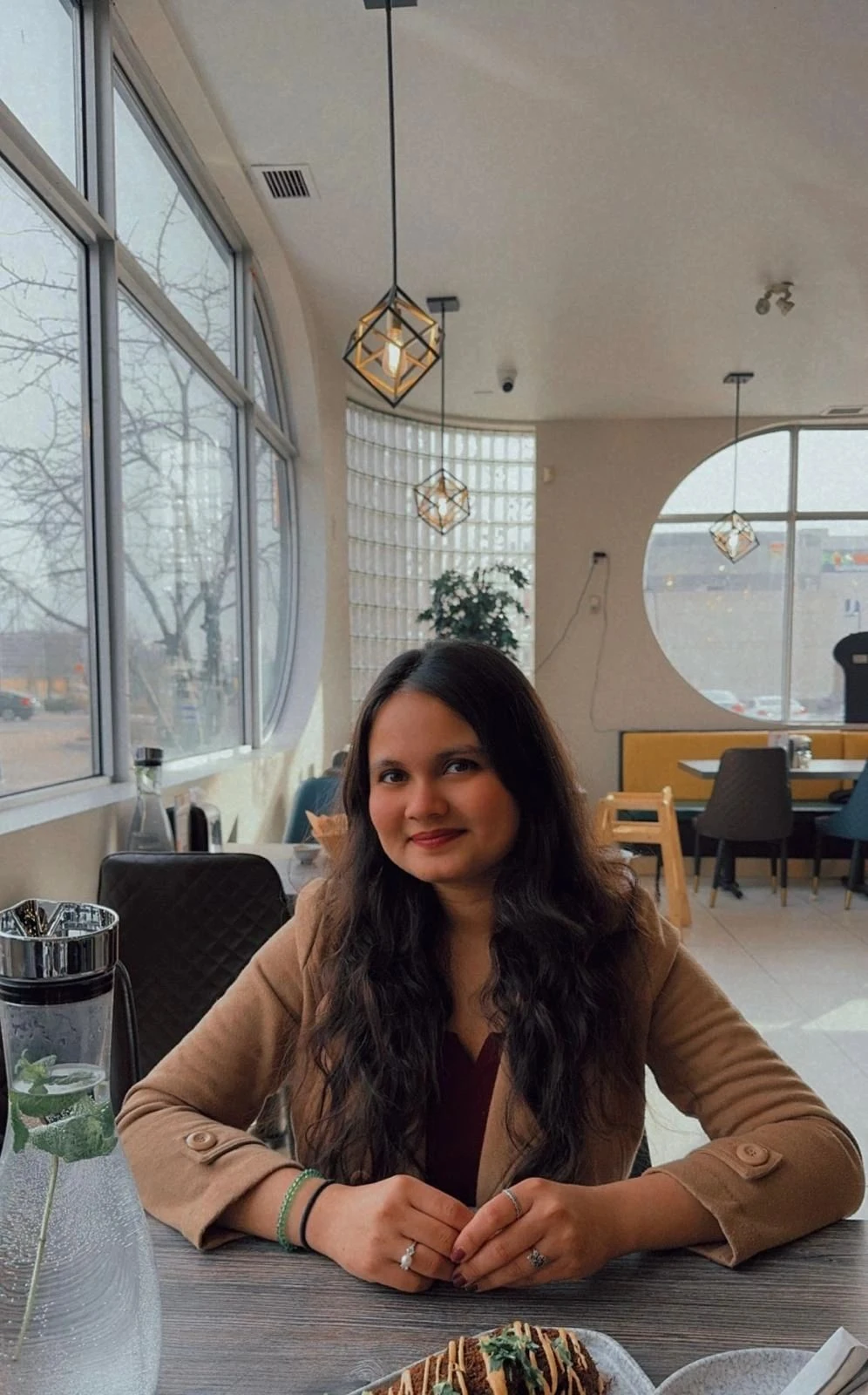 Twisha Mehta sitting at a sunlit café
